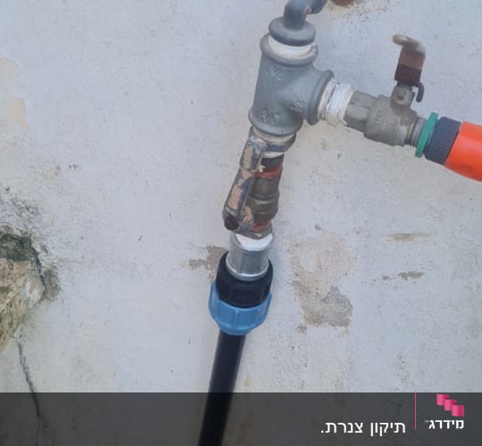 צינור מים עם ברז ומחבר על קיר חיצוני